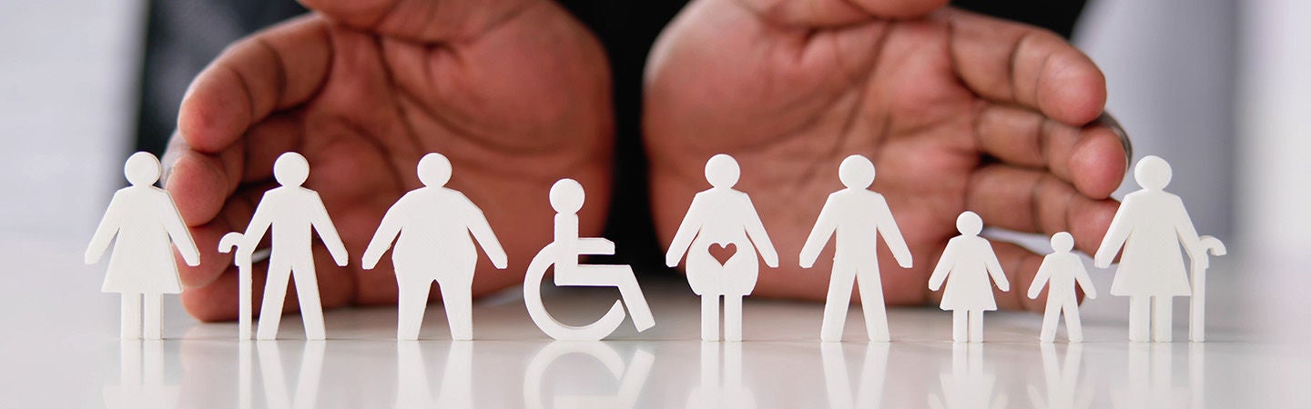 Hands displaying diverse and differently-abled paper figures representing inclusion and belonging