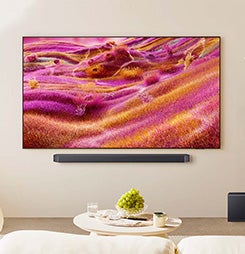 Samsung Neo QLED 4K TV displaying pink/orange art. A slim soundbar is mounted below.