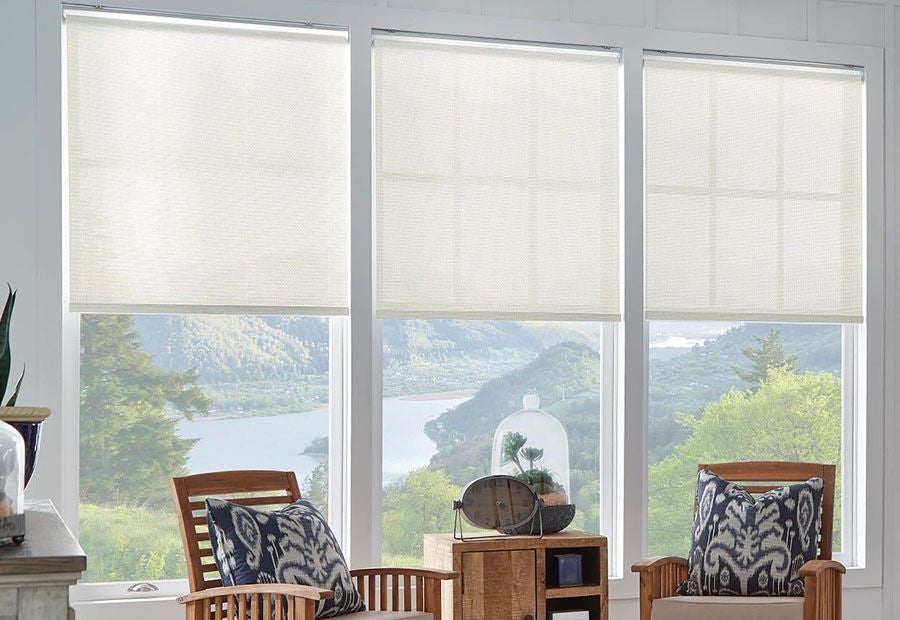 Three cream Bali solar shades half-lowered over large windows with a scenic mountain view.