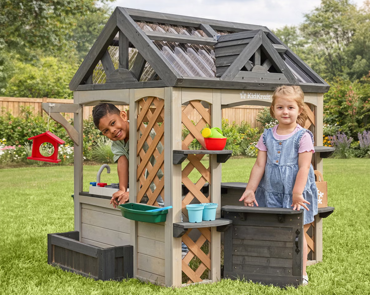 Two children playing in a wooden playhouse