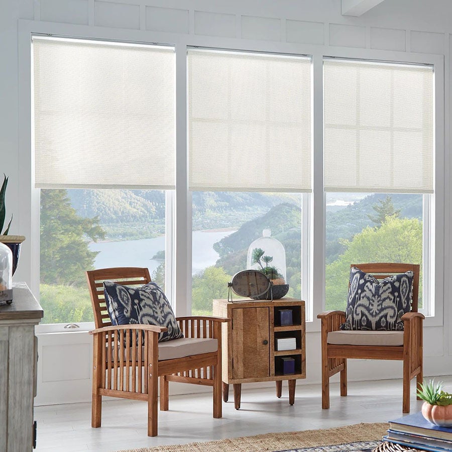 Three cream Bali solar shades half-lowered over large windows with a scenic mountain view.