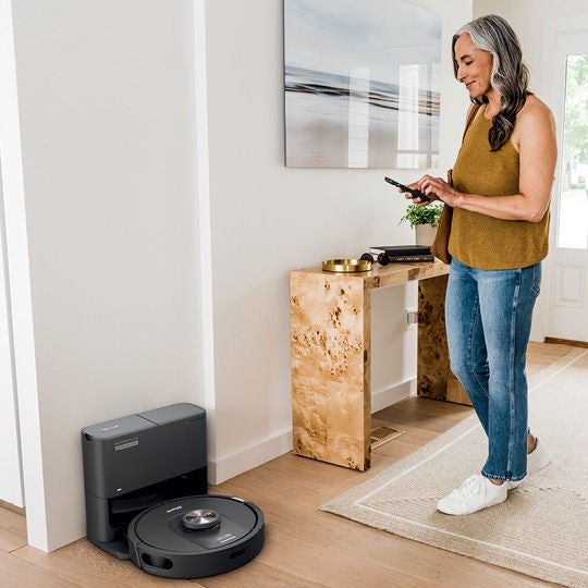 Woman using her phone to access her robot vacuum.