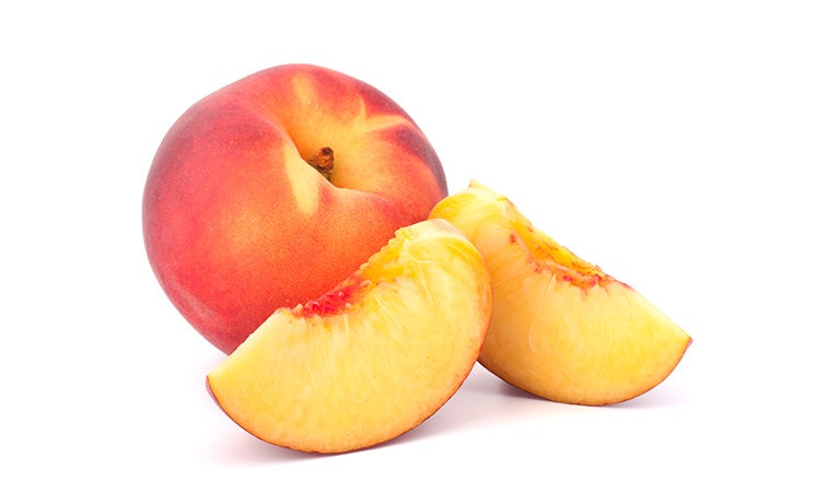 A whole peach with slices of peach in front of it