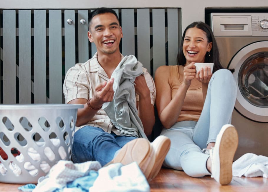 two people sitting on the floor doing laundry