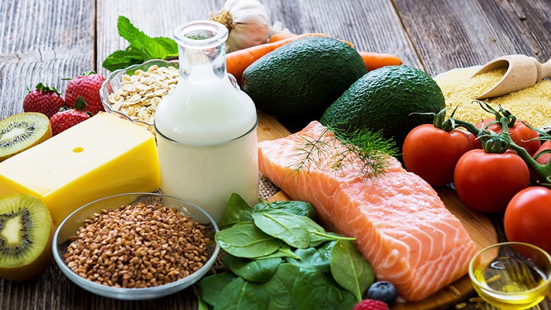 Variety of healthy fresh foods - salmon tomatoes milk cheese grains avocados fruits
