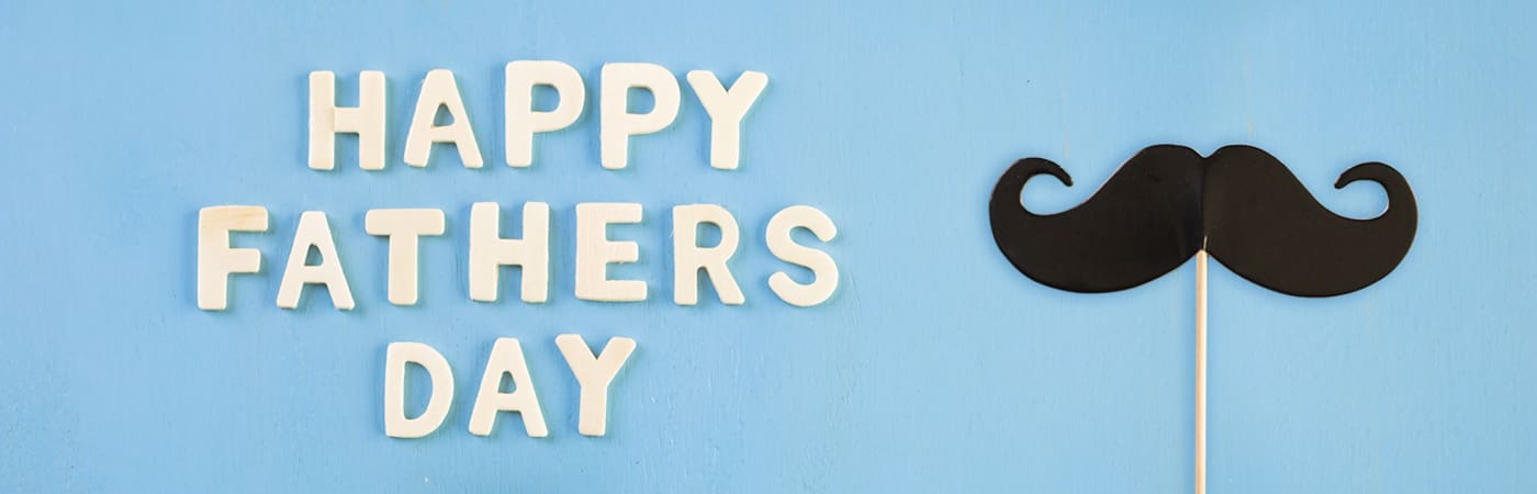 Happy Father's Day written in block letters, sitting next to a paper moustache.
