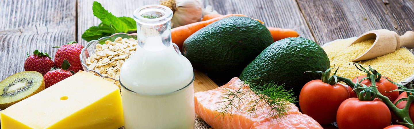 Variety of healthy fresh foods - salmon tomatoes milk cheese grains avocados fruits