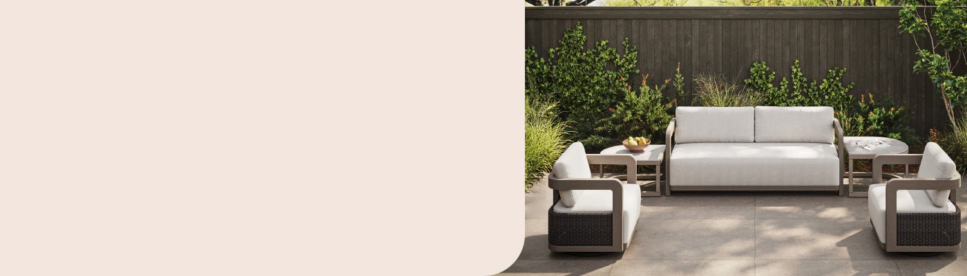 Modern Agio patio set with a cream sofa, two swivel chairs, and side tables on a stone patio.