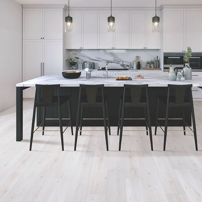 Modern and open kitchen concept with a marble-topped, dark-gray island, white cabinets and light gray wood-grain laminate floor.