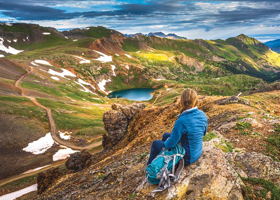 woman sitting on a rock looking at a lake