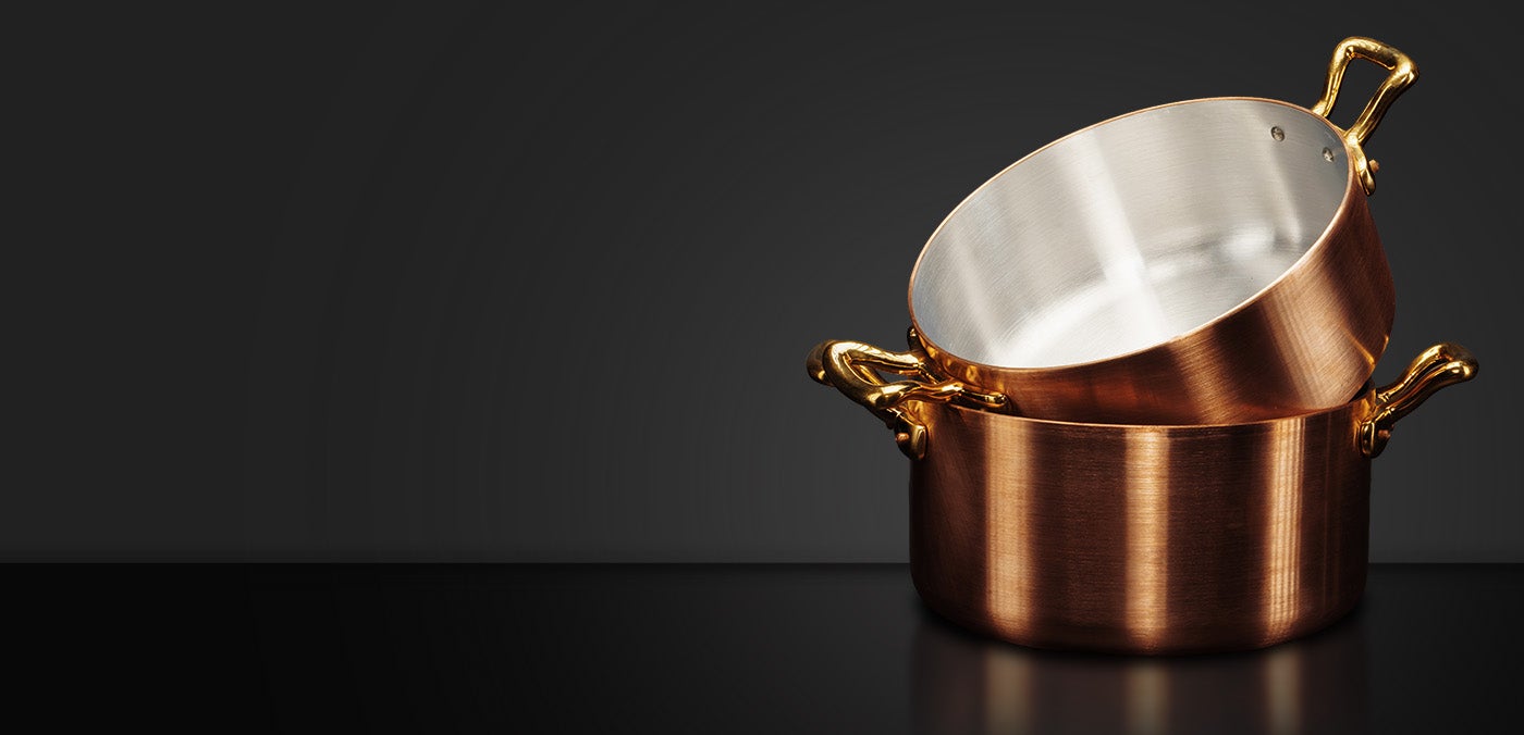 Stacked copper pots on dark background